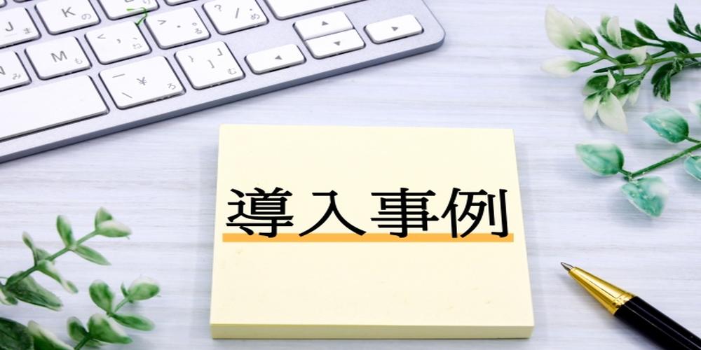 「導入事例」と書かれた付箋とパソコンのキーボード、ペン、観葉植物が並ぶデスク上のイメージ写真
