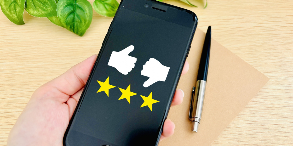 スマートフォン画面に表示された親指の上げ下げアイコンと三つ星評価。レビューや評価のイメージ