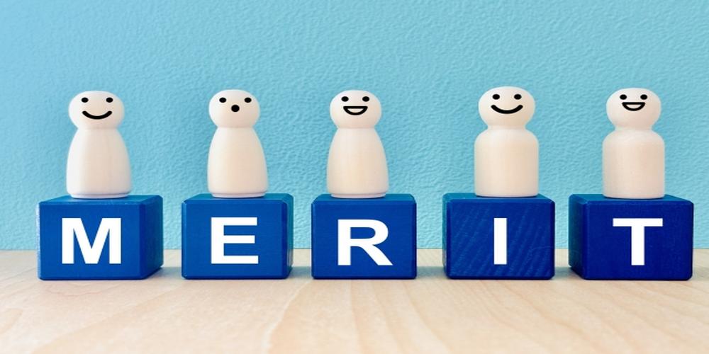 「MERIT」と書かれた青いブロックの上に笑顔の木製ピースが並ぶポジティブな印象の画像（メリットの概念）