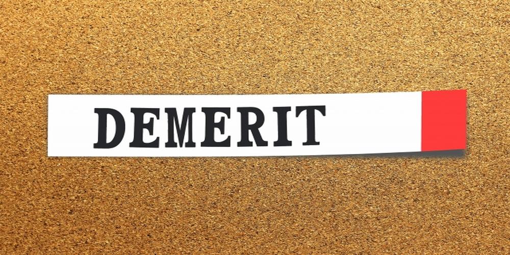 コルクボードに貼られた白い紙に「DEMERIT」と黒文字で記載され、右端に赤いラインが入っている画像
