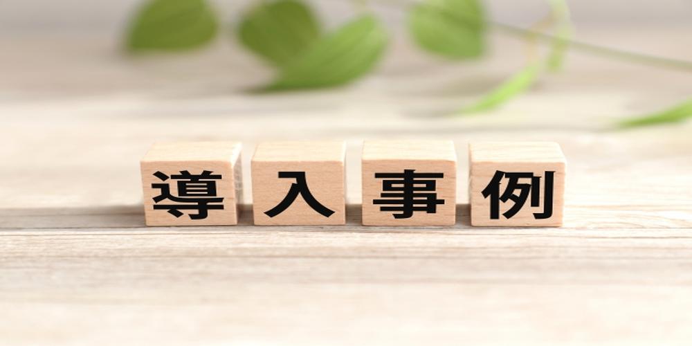 木製ブロックに「導入事例」と書かれた文字が並べられている画像（背景に観葉植物の葉）