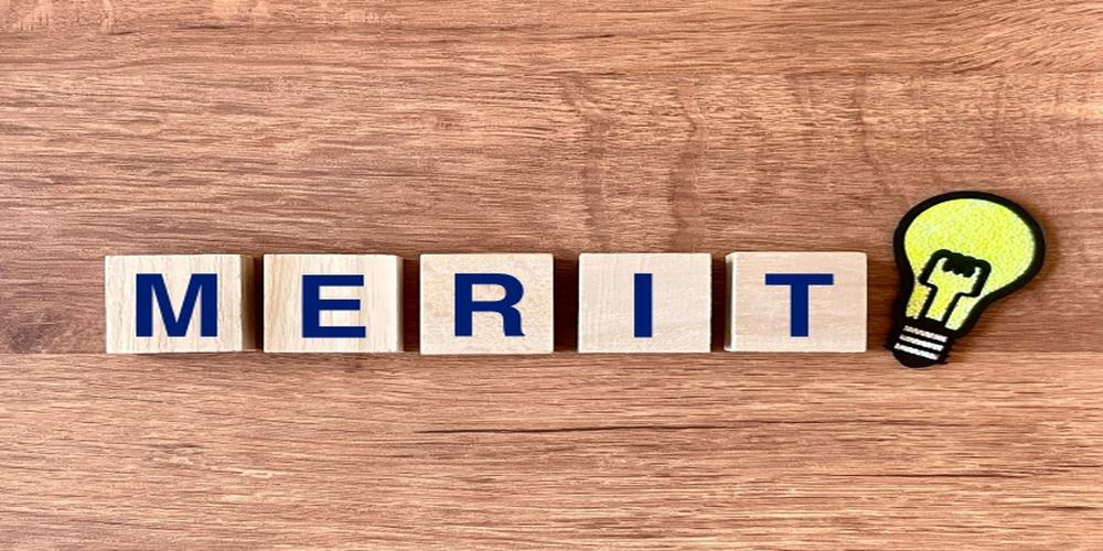 木のブロックに「MERIT」と書かれた文字と電球のイラストが並ぶイメージ画像（メリット・利点の概念）