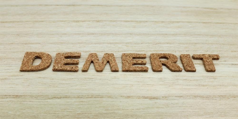 木目調の背景にコルク素材の文字で「DEMERIT」と並べられた画像（デメリットのイメージ）