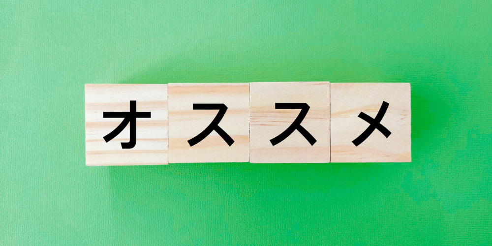 この画像は、木製のブロックに黒色の文字で「オススメ」と書かれ、緑色の背景に並んでいる様子が写っています。