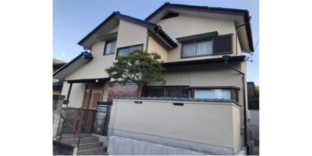ベージュの外壁をまとった和風住宅の正面が写され、塗装後のきれいな仕上がりを示す施工事例写真