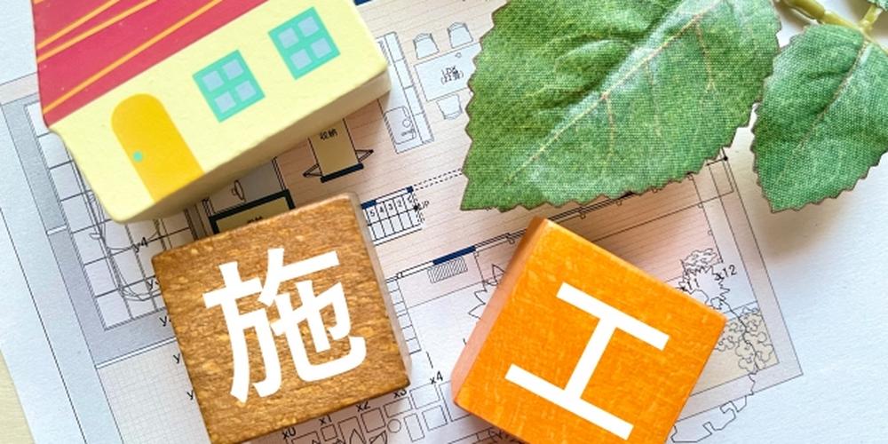 施工計画と住宅模型が配置された設計図の上に置かれたイメージ写真